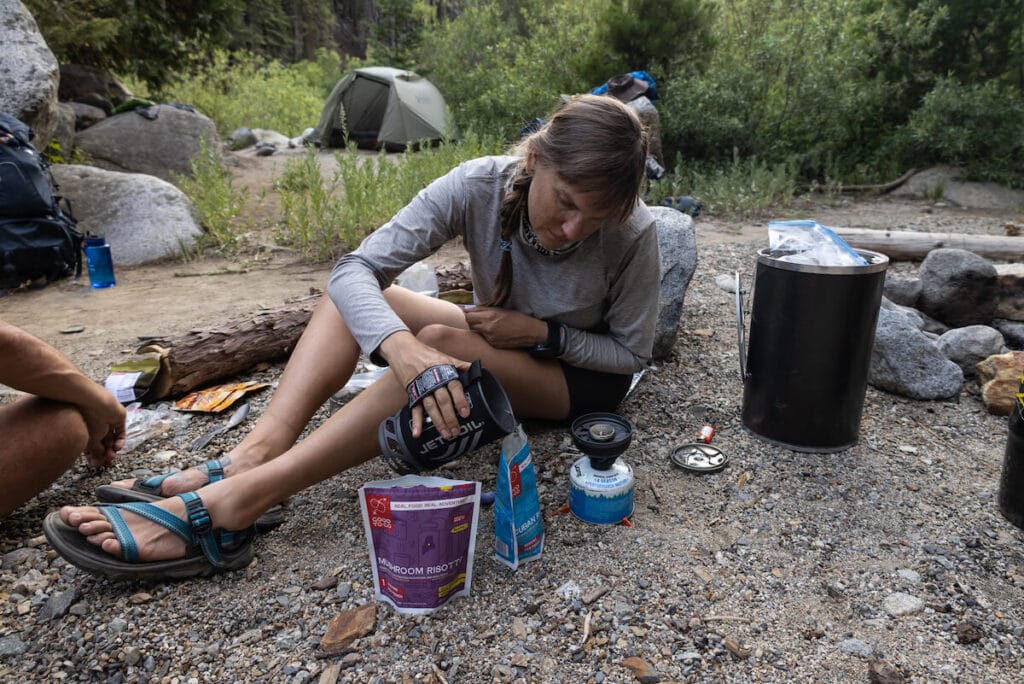 Woman pouring hot water into a backpacking meal from a JetBoil Flash stove