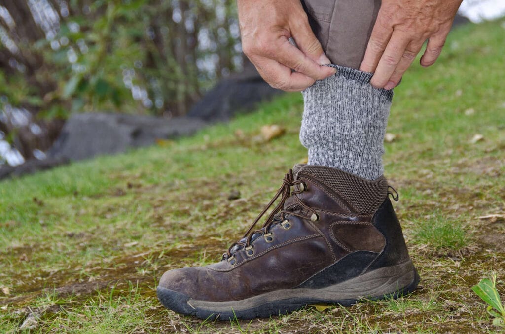 Hiker tucking pant legs into socks for protection against ticks