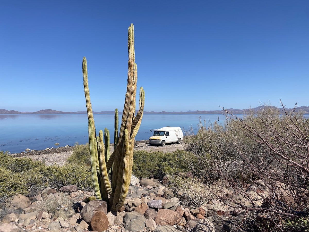 A white campervan on the beach doing Baja van life road trip