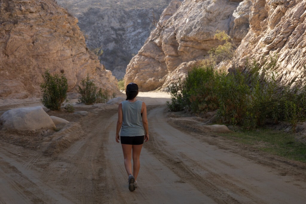 A woman hikes in a shady canyon wearing Oboz Sawtooth X low