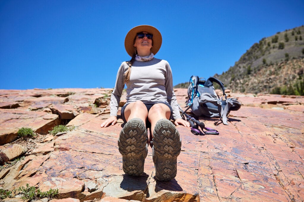 a woman sits on the ground during a hike wearing Oboz Sawtooth X