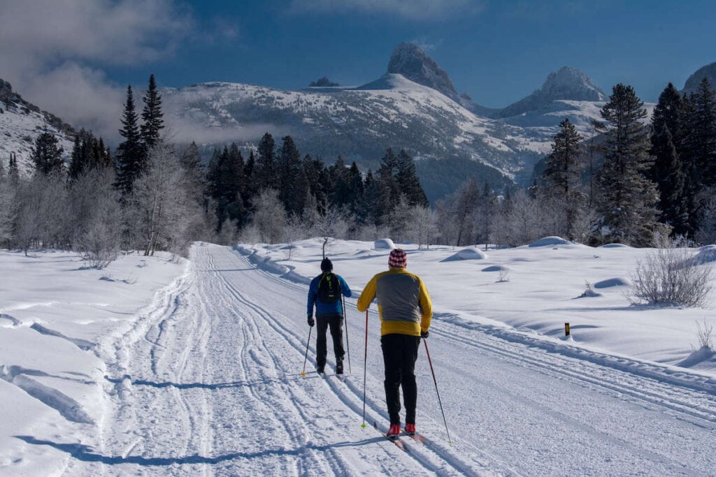 Two nordic skiers on groomed trail outside Driggs, Idaho with the Tetons in distance