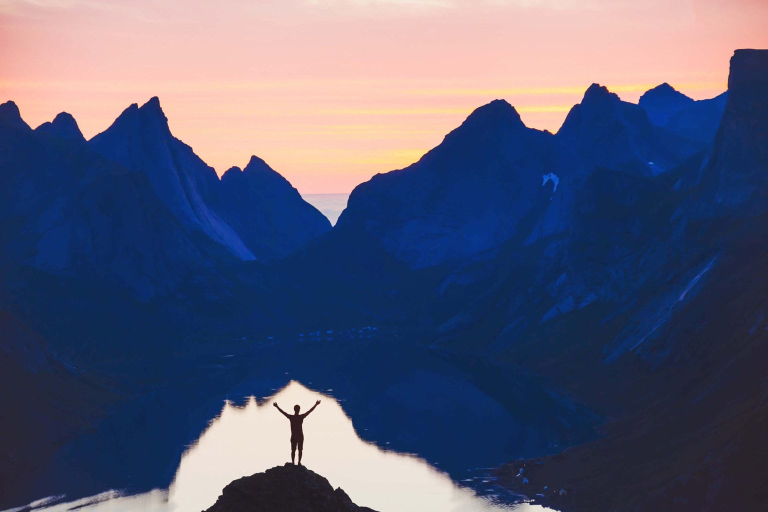 ilhouette of person with raised hands on beautiful mountain landscape at sunset
