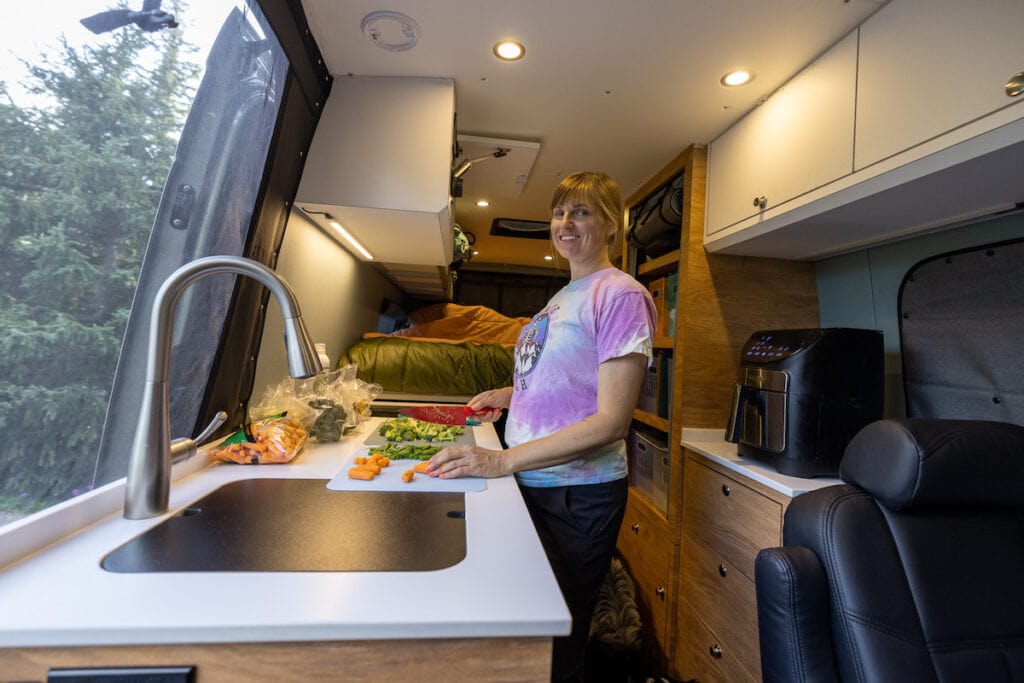 Bearfoot Theory founder kristen Bor inside her Sprinter Van chopping veggies