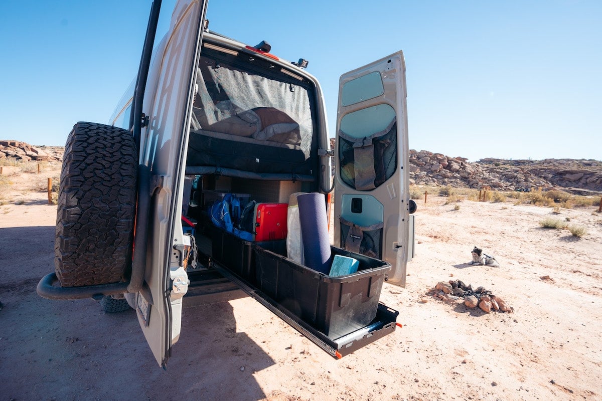 Gear slider in the back of Sprinter with two black plastic bins with outdoor gear inside them