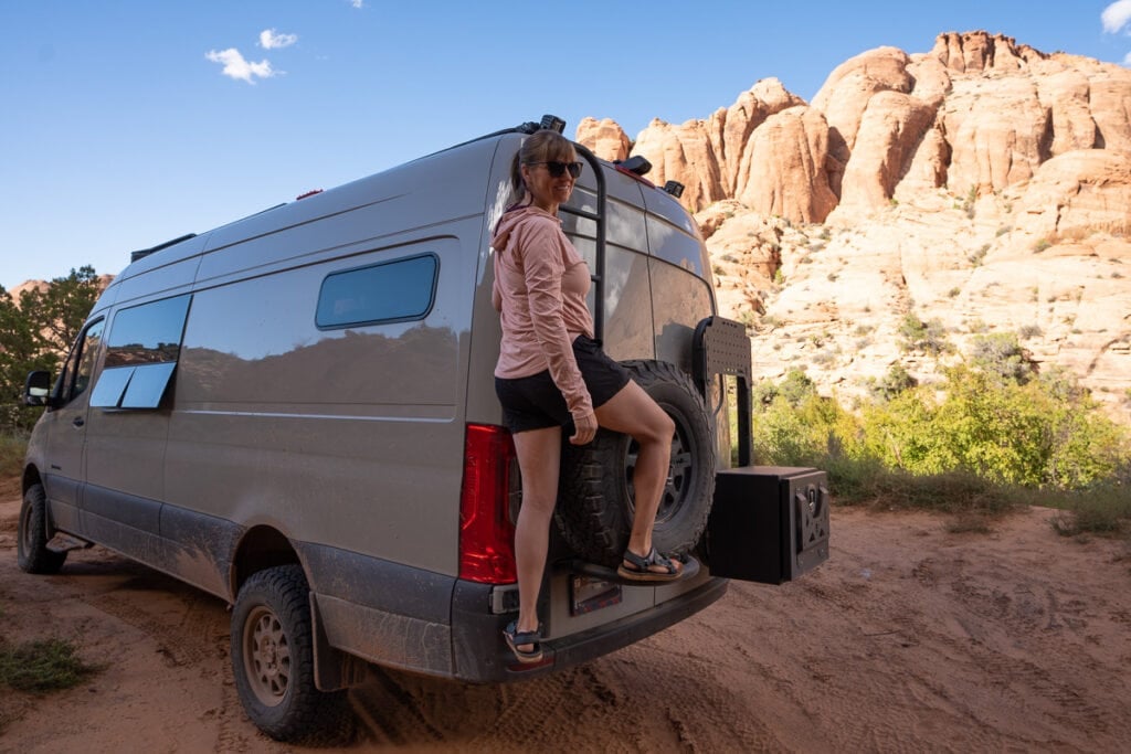 Climbing the Owl Vans Ladder on the back of a 4x4 Sprinter Van designed for outdoor adventure