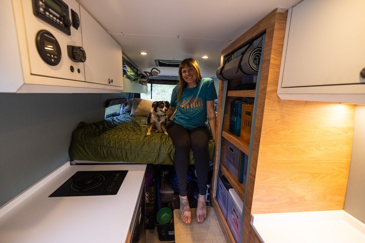 Kristen Bor sitting on bed in sprinter van with dog