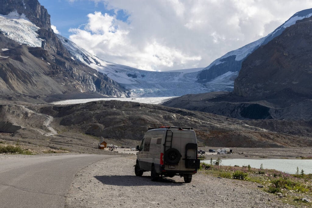 Sprinter van parked off road in front of Athabasca Glacier on Icefields Parkway in Canada