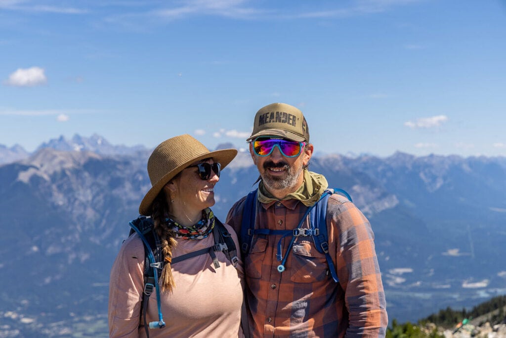 Kristen and Ryan in front of a mountain background. Ryan is wearing the REI Wallace Lake Flannel shirt, one of the best gifts for outdoor lovers, hikers, and men