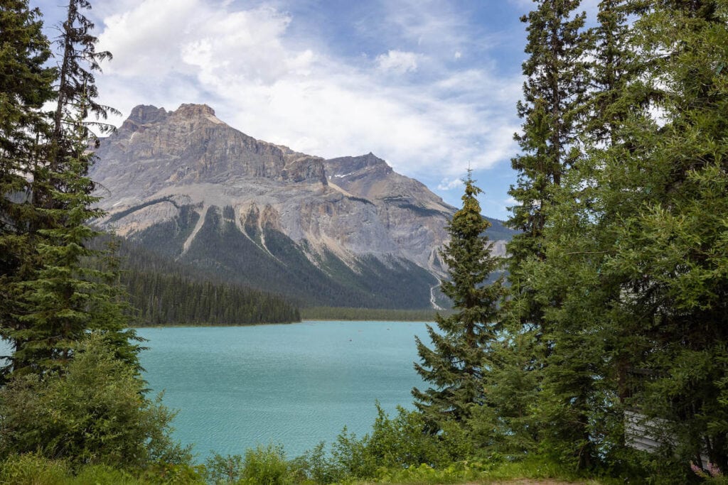 View of Emerald Lake in Yoho National Park from trail with mountain peak towering above