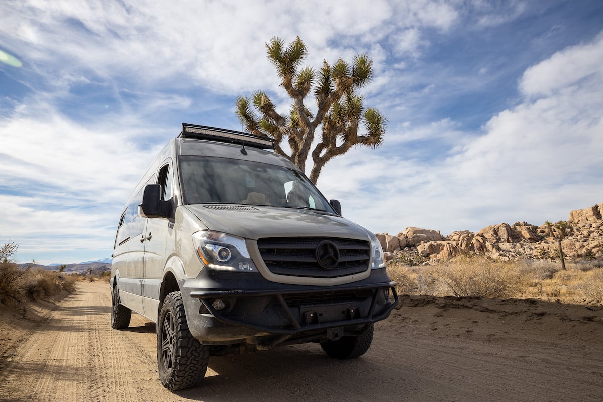 A Sprinter van parked near to a Joshua Tree in Joshua Tree National Park