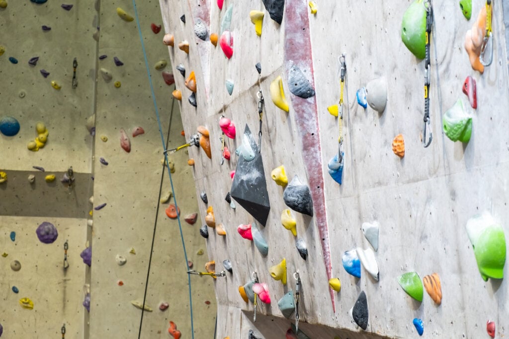 A close up shot of an indoor rock climbing wall with ropes