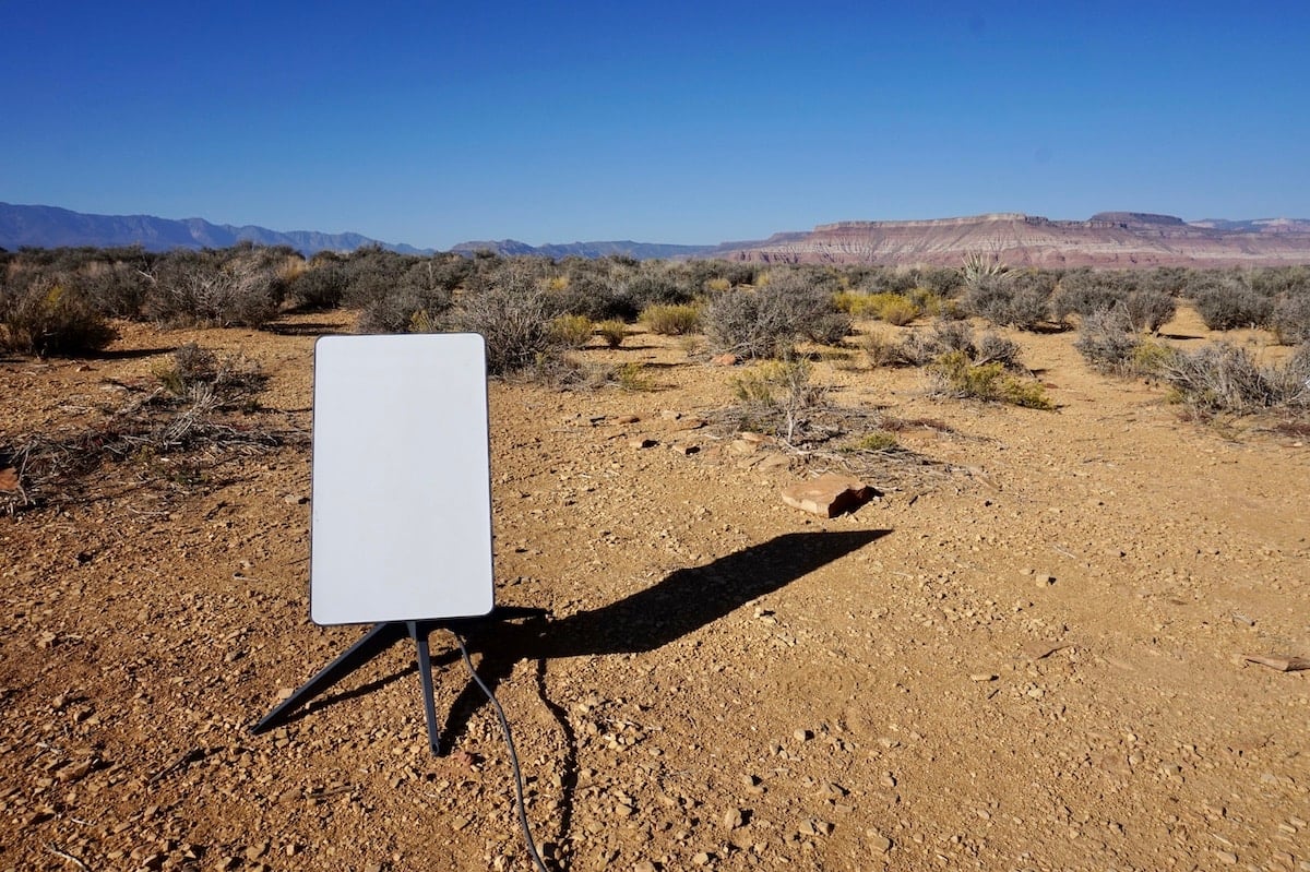 Starlink set up in a desert with sand and a blue sky in the background