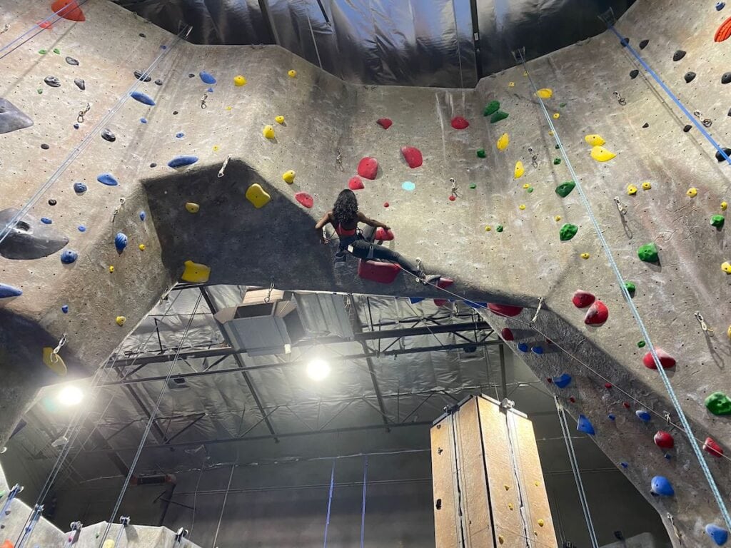 A woman lead climbs at an indoor rock climbing gym