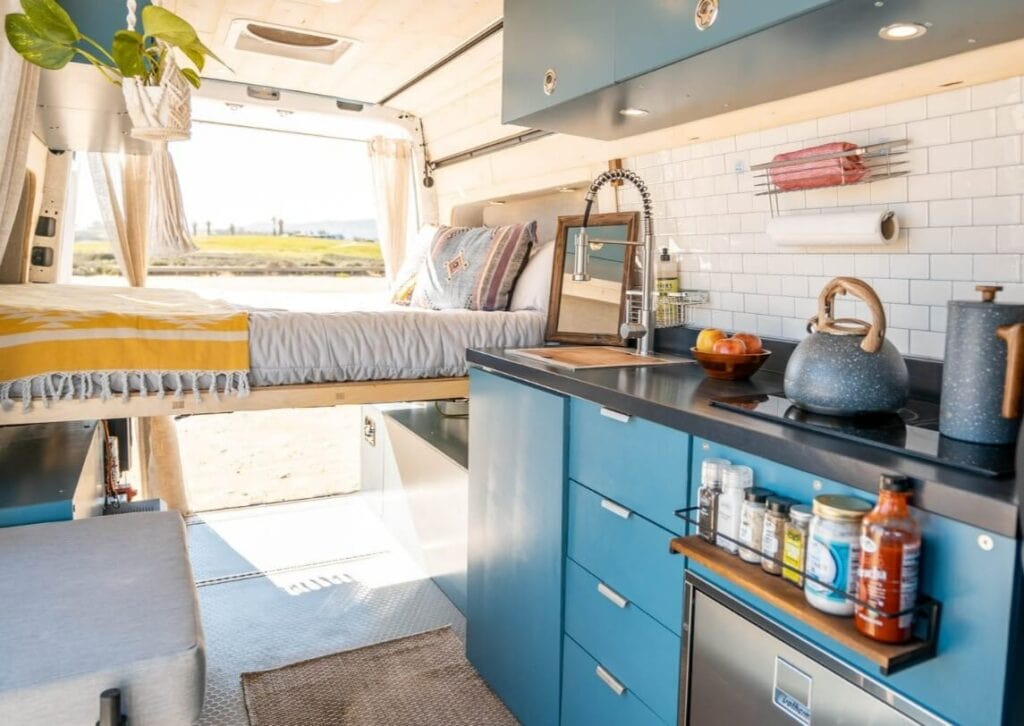 Bright at airy interior of a campervan with blue cabinets and white walls