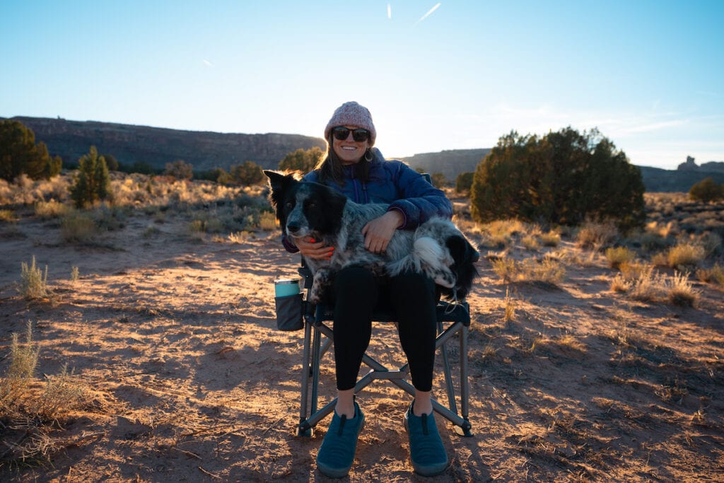 Woman with a dog sitting in her lap in the desert