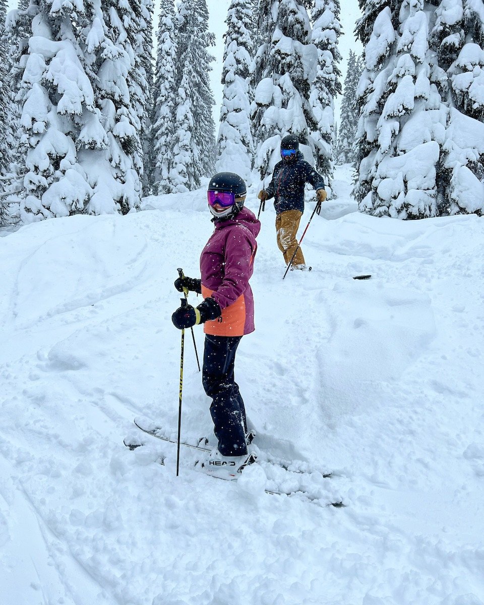 Two skiiers stopped in the snow while skiing in Revelstoke BC on the Powder Highway