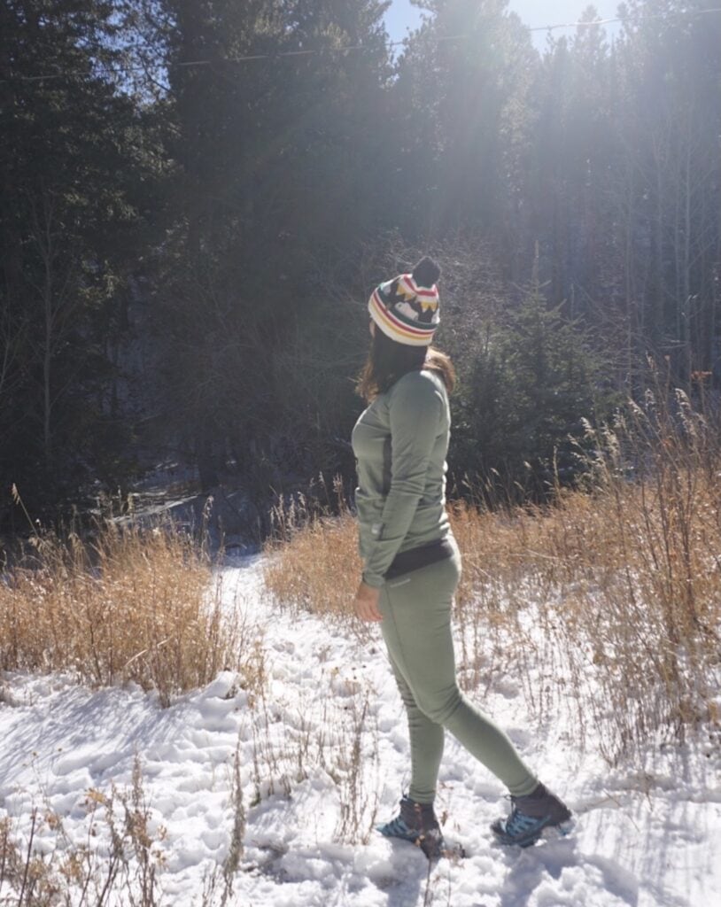 A woman wearing the Artilect Flatiron 185 Crew Top and leggings in the snow