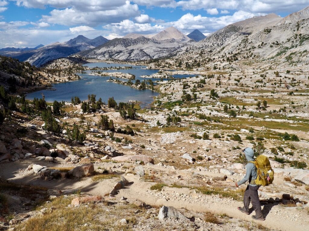 A manh hikes on a rocky trail above Marie Lakes on the JMT