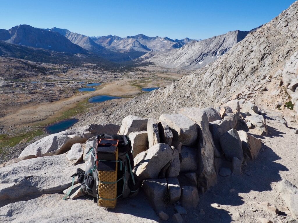 A backpacking pack set down on the trail at the top of Mather Pass on the John Muir Trail