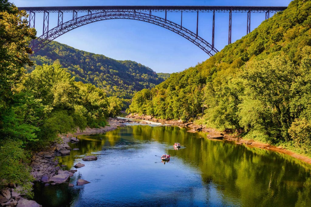 Rafters floating down river in New River Gorge National Park in West Virginia with lush forest lining both banks