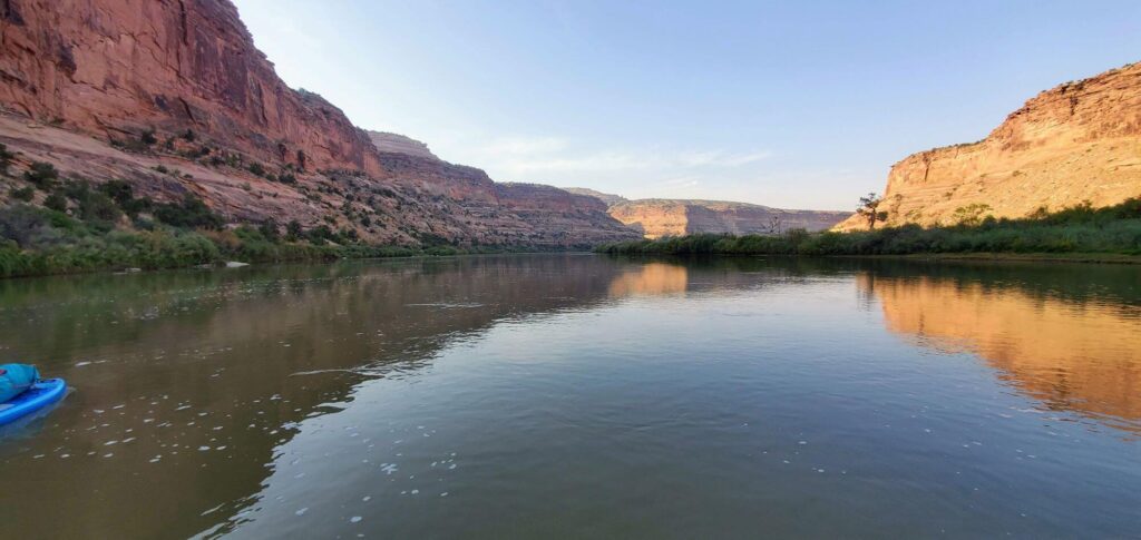 View from water of Colorado River with tall rock bluffs on either side