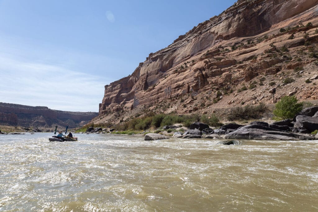 Packraft coming down river with small rapids on Ruby-Horsethief Canyon section of the Colorado River