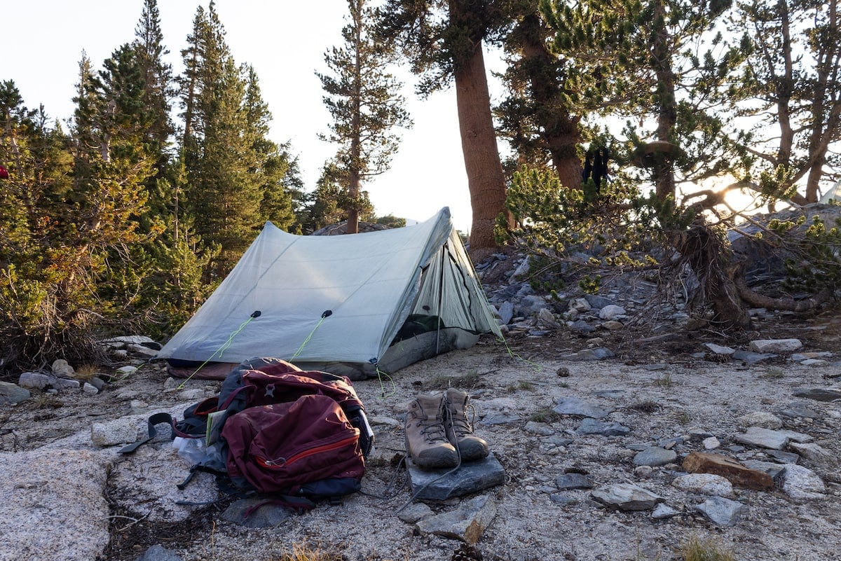 Ultralight Zpacks Triplex backpacking tent set up with a backpacking pack and boots in front