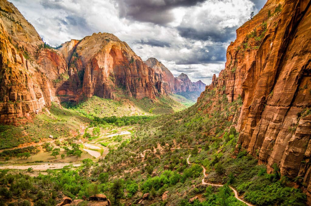 Landscape view of Zion National Park with tall red rock cliffs towering over lush green valley