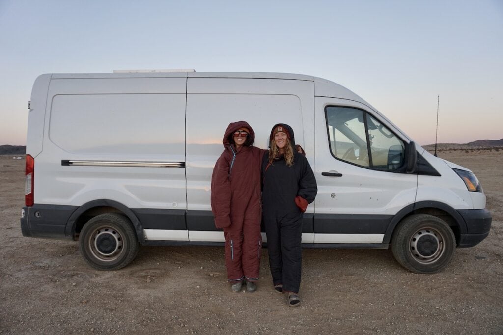 Two women wearing Selk'Bags standing next to a white Ford Transit van