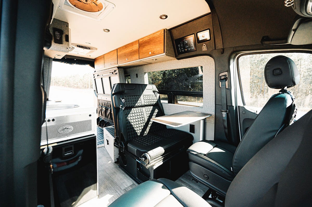 Interior of the Storyteller Overland Classic MODE van showing the front seats swiveled to create more seating space when camped