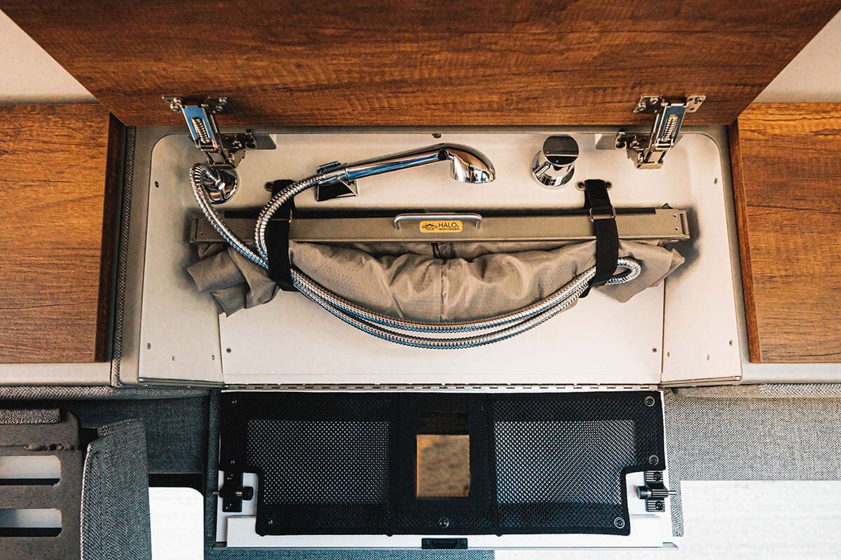 Storyteller Overland's patented HALO hidden shower system stows in the overhead cabinet when not in use