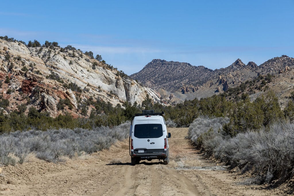 The Storyteller Overland Classic MODE AWD van driving off-road on a muddy dirt road in Southern Utah