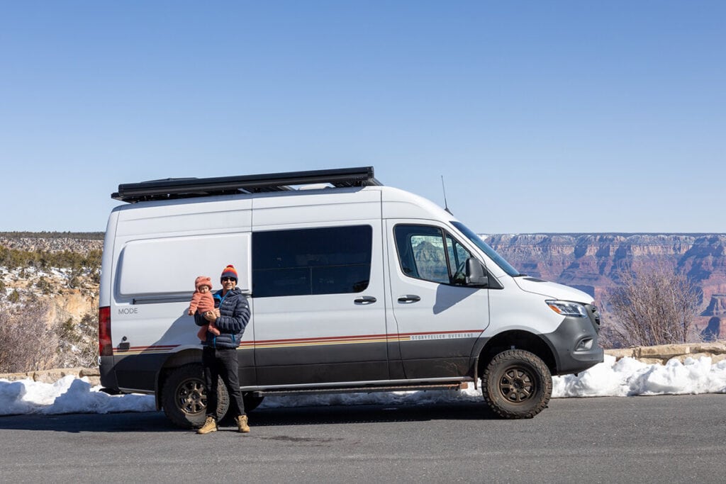 A man holding his toddler standing in front of a Storyteller Classic AWD MODE van with the Grand Canyon in the background