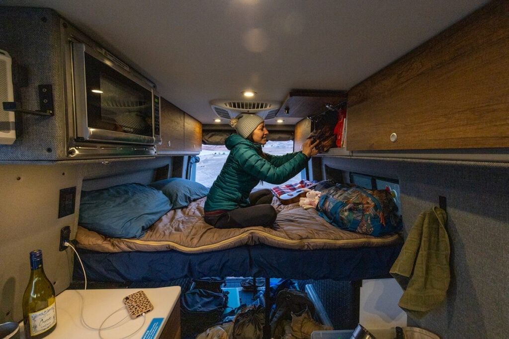 Opening the overhead cabinet storage space inside the Storyteller Overland Classic MODE van