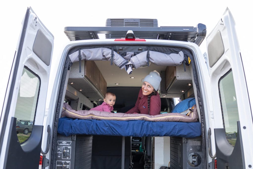 View into the back of a Storyteller Overland Classic MODE van showing a mom and toddler looking out