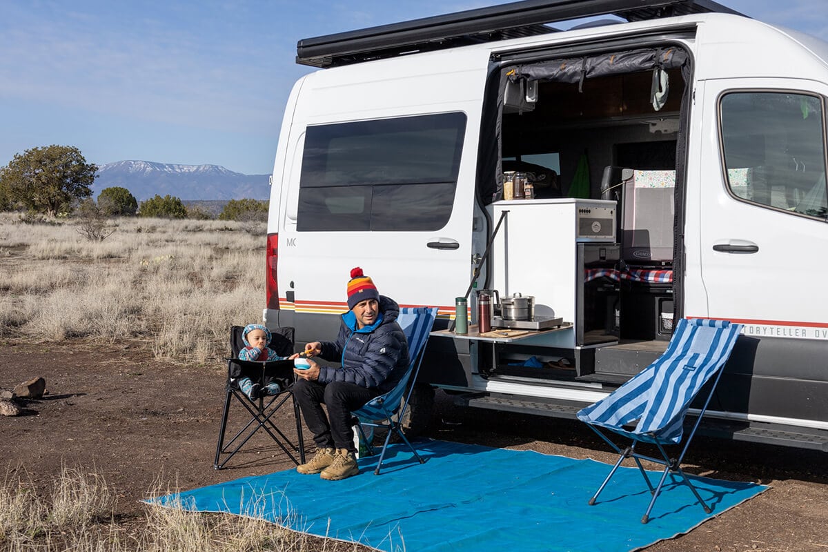 A family camped off-grid near Sedona in the Storyteller Overland Classic MODE van showing the galley/kitchen and outdoor patio area