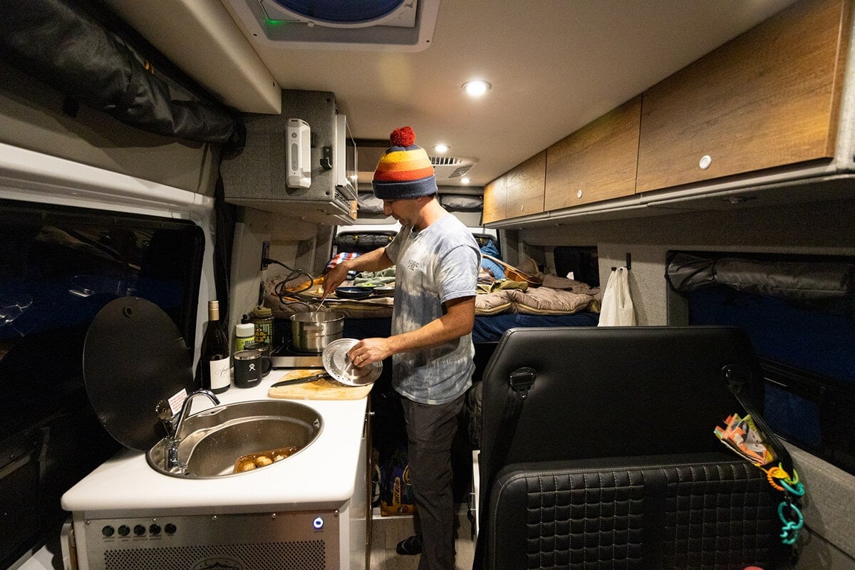 Cooking in comfort inside the Storyteller Overland Classic MODE van on a cold night