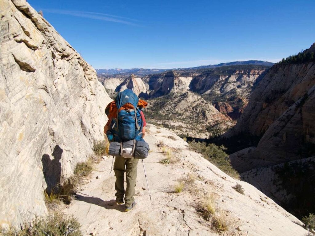 Backpacker hiking on rock ledge in high country of Zion National Park