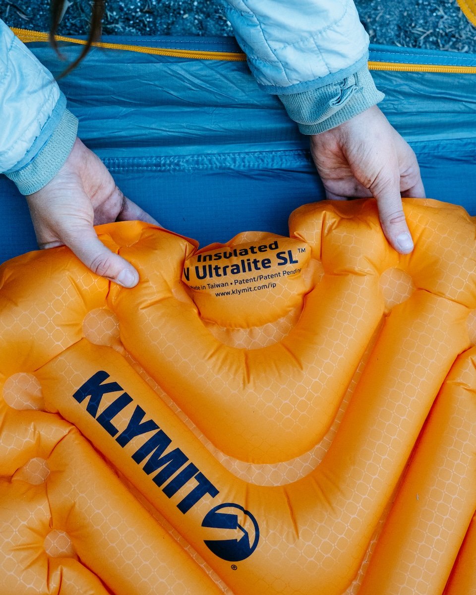 Hands placing the Klymit Insulated V Ultralite SL into a tent