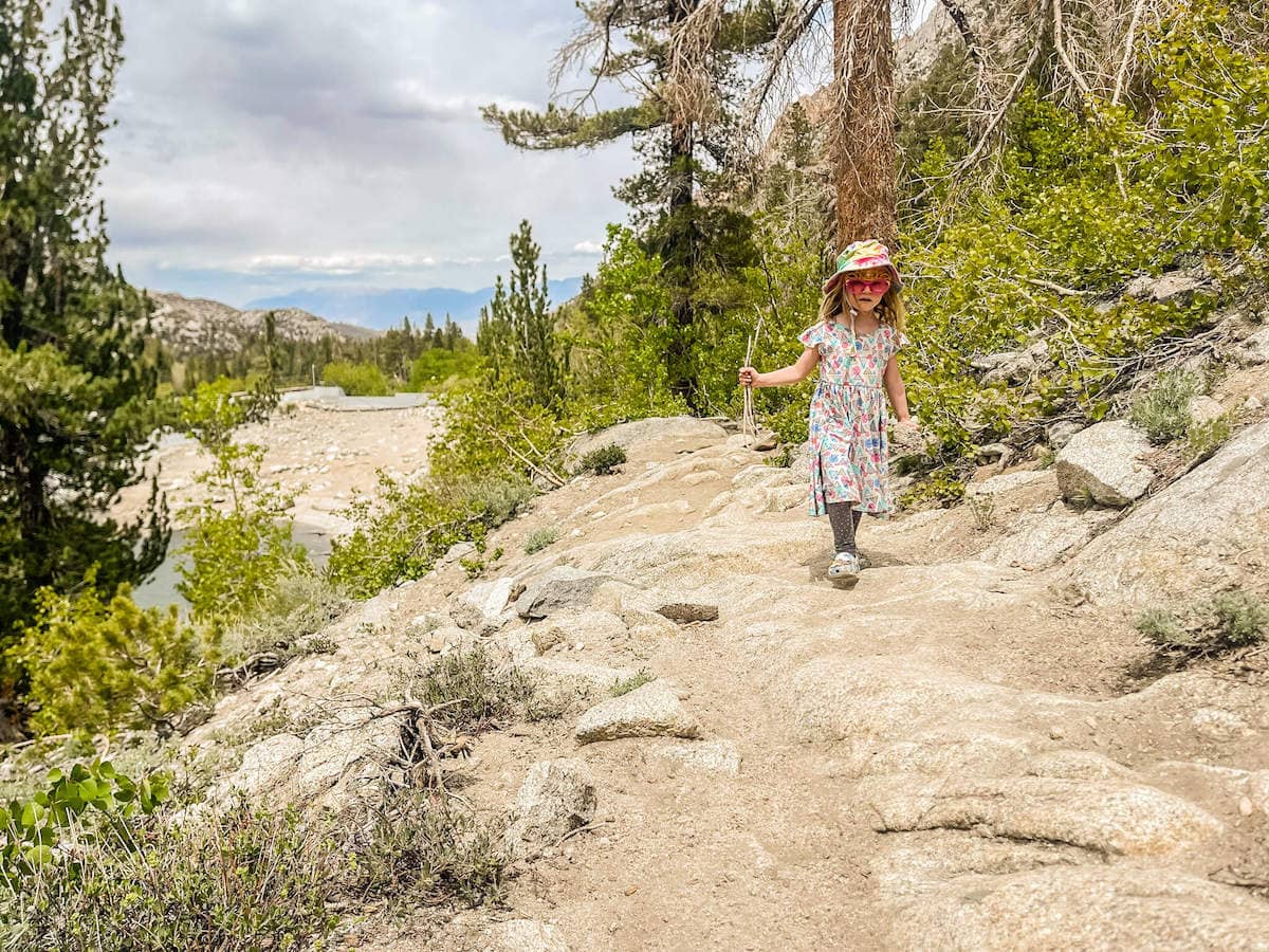 Young girl hiking on rocky trail in Sierra Nevada mountains in California
