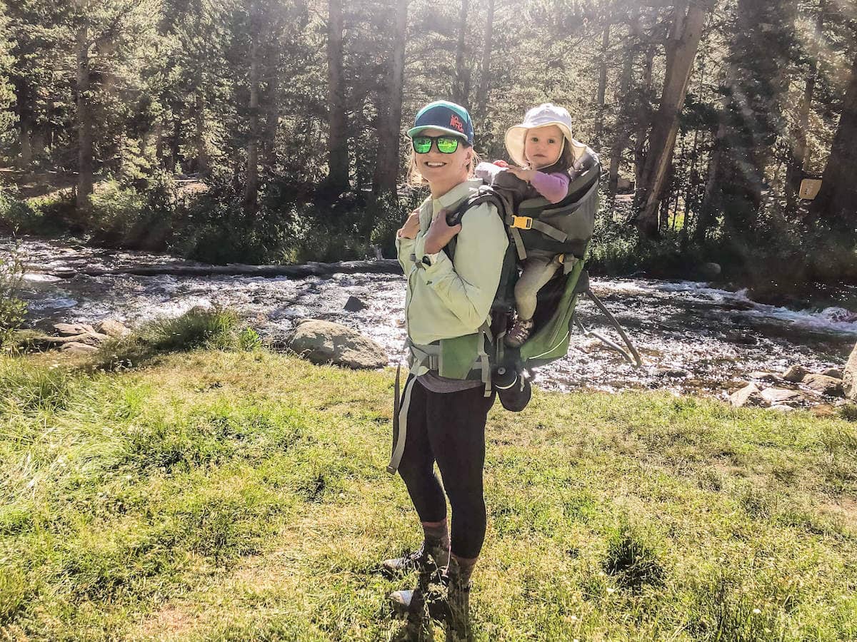 Woman carrying child in a kids hiking backpack