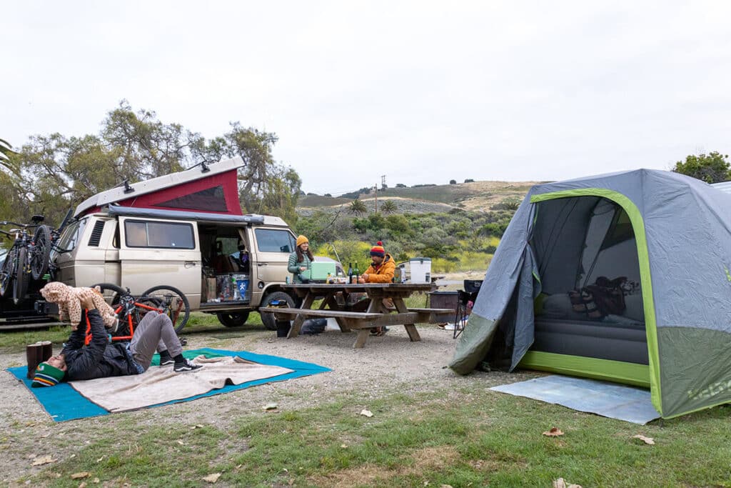 Group of campers at a campsite, playing with a kiddo and chatting