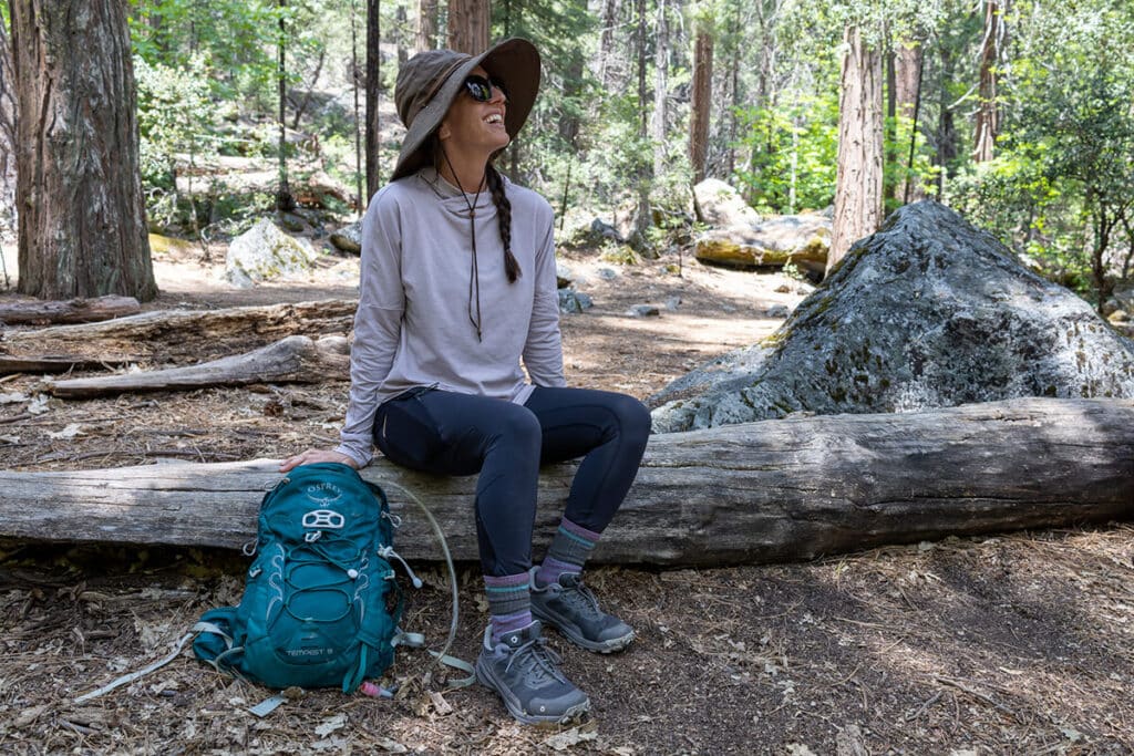 Woman hiker taking a break sitting on a log wearing the Oboz Katabatic hiking shoes
