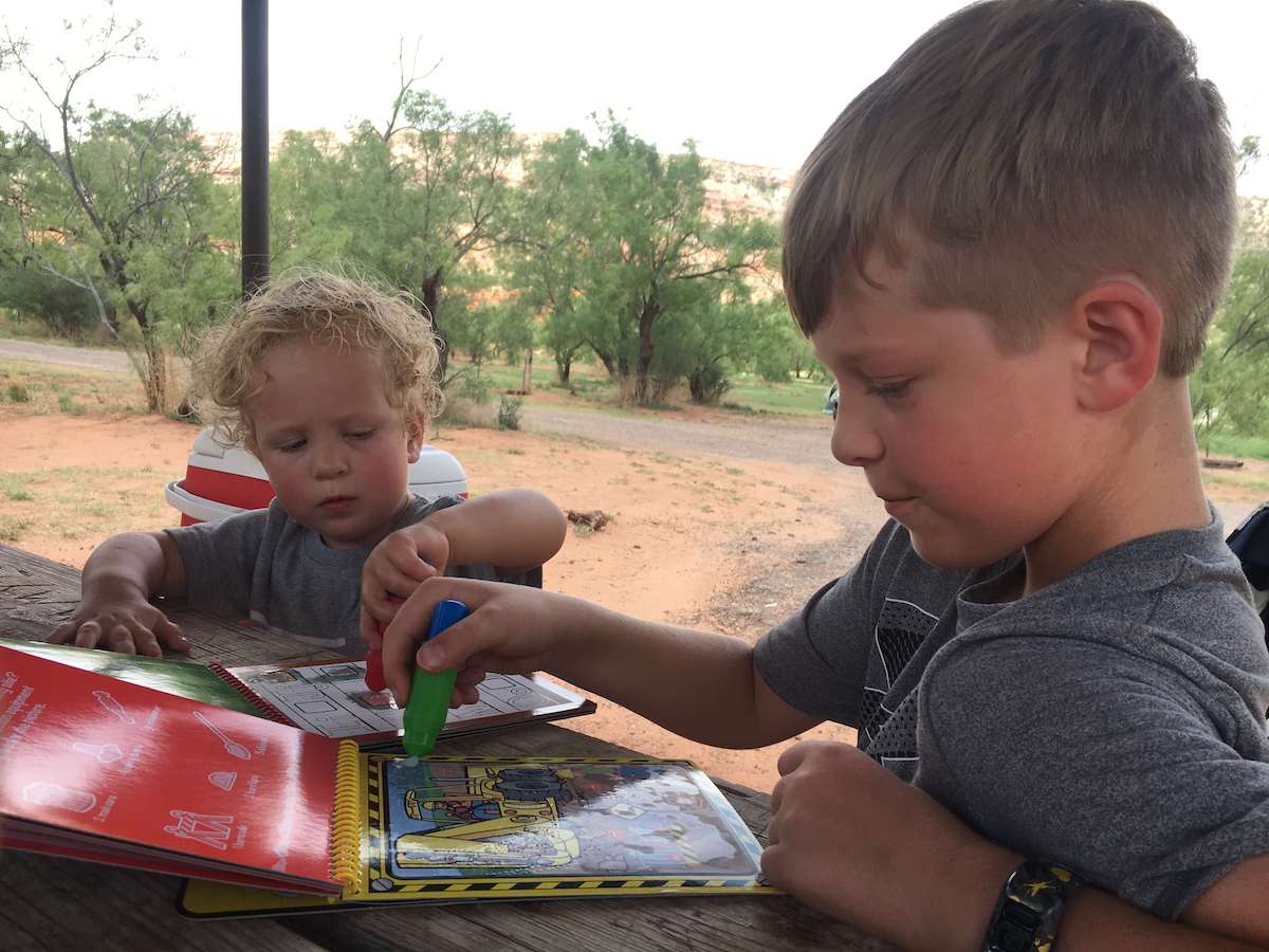 Two kids doing activities at table at campground