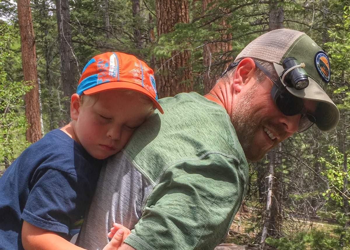 Man carrying sleeping child on his back on a hike