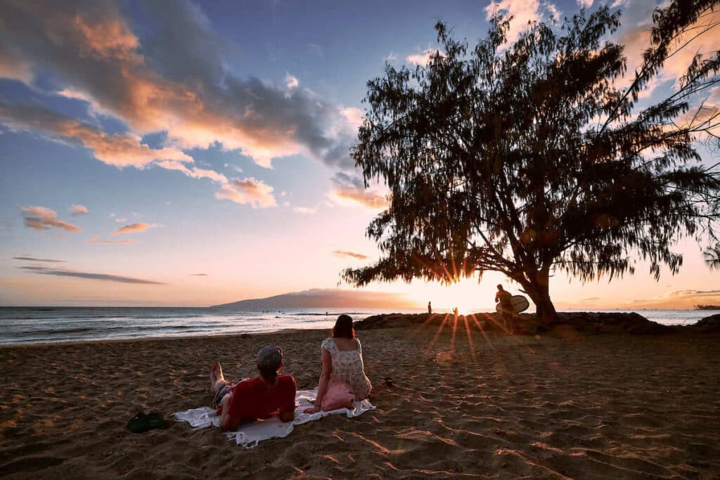 Couple sitting on beach on Maui at sunset