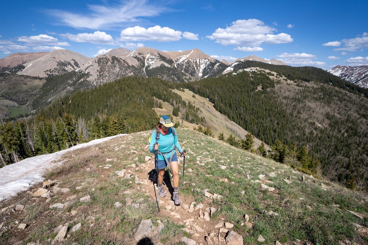 Kristen Bor hiking up a mountainous trail using hiking poles and wearing oboz katabatic lt hiking boots