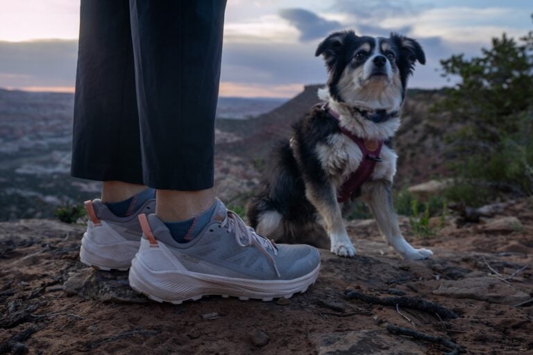 Womens ankles wearing Oboz Katabatic LT lows standing next to a mini Australian shepherd