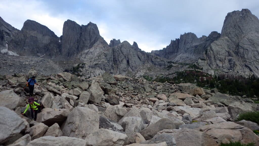 two hikers scramble through a boulder field in Cirque of the Towers Wyoming